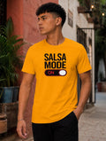 Male model wearing a bright yellow “Salsa Mode ON” graphic t-shirt with bold black lettering and switch design, styled casually in an outdoor street setting. Fun salsa dance apparel for Latin dance lovers, social dancers, and salsa lifestyle fashion.